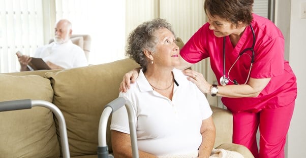 A nurse checking on an elderly woman.