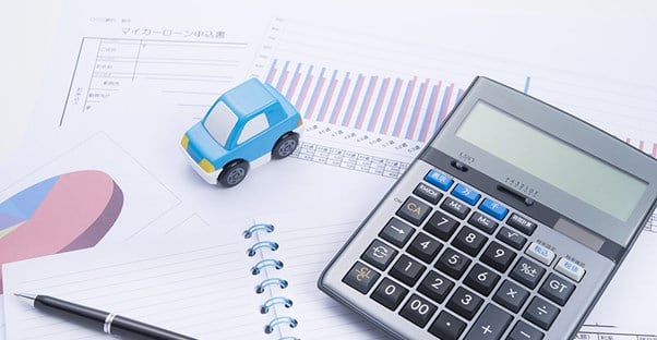 calculator and car on notebook pen and auto loan paperwork