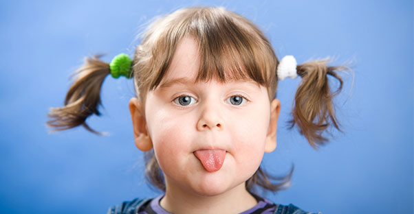 Little girl with weird pigtails sticks out her tongue