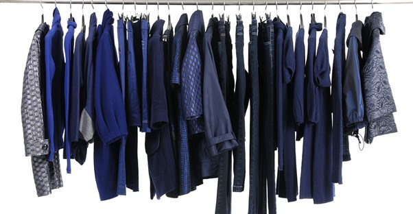 Blue articles of clothing hang in a closet