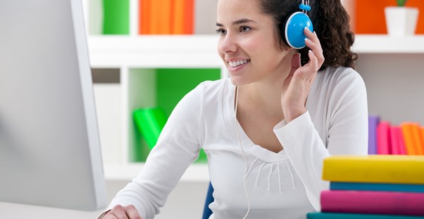 Girl wearing headphones smiles at her computer