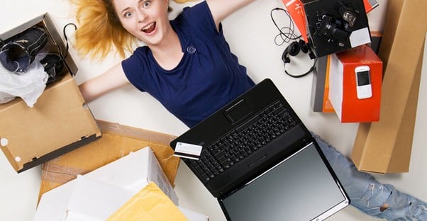 Woman laying on floor with laptop and surrounded by purchases 
