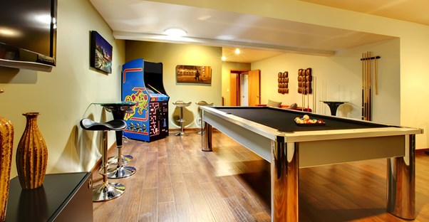 a man cave with pool table, arcade machine, and bar stools