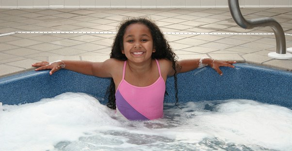 A little girl enjoying a hot tub as she follows the safety rules.