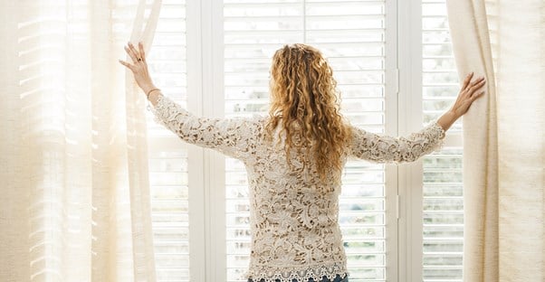 Woman opening her economical window treatments