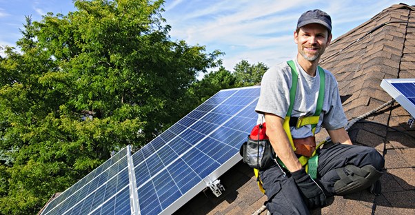 A man installing solar panels onto a roof