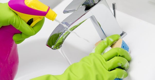 Woman cleaning a sink with a DIY cleaner.