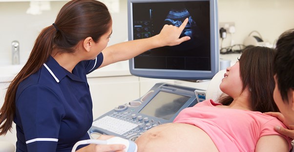 An ultrasound tech showing a pregnant woman her baby.