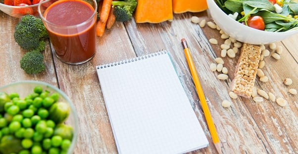 A note pad surrounded by foods for vegan and vegetarian diets