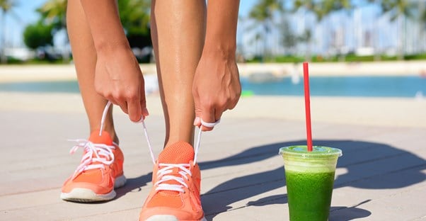 A vegan lacing up her sneakers while drinking green juice