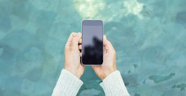 Woman holding her phone over a pool of water