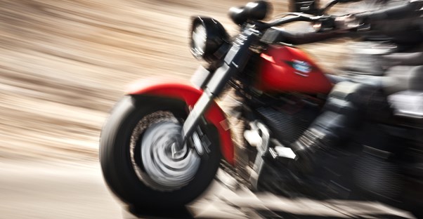 a red motorcyle zooms down the highway in a blur