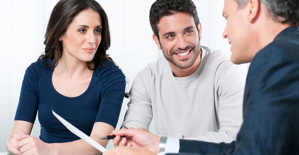 Attractive couple speaking to a man explaining paperwork to them