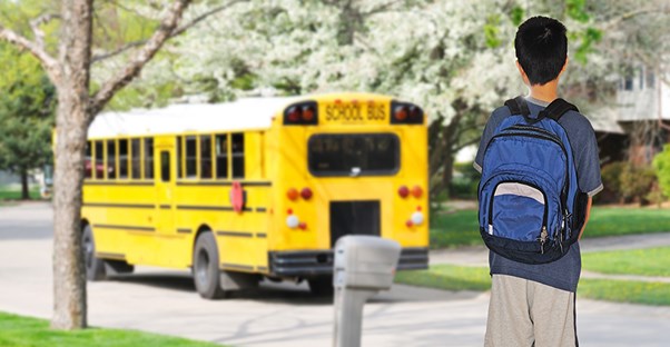 a student waits for a school bus symbolizing a concept for a charter school
