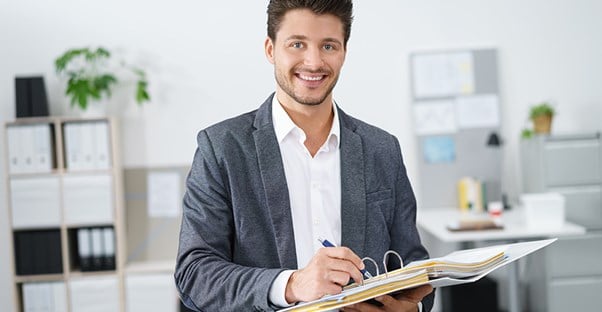 male employment lawyer in casual suit smiling and writing in binder