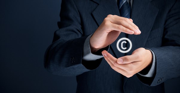 Man in a suit holding the copyright symbol in his hands.