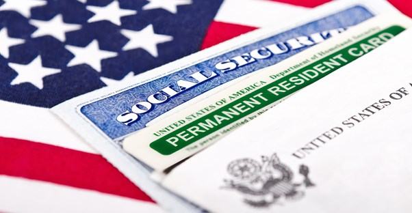 a social security and U.S. permanent resident card lying on top of an American flag