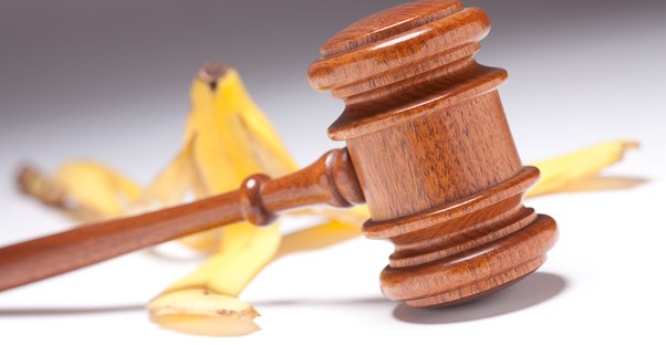 A banana peel laying on the ground behind a wooden gavel to represent how accident injury lawyers legally achieve compensation for injured individuals.