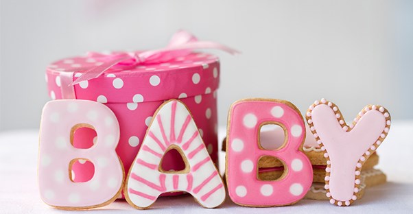 baby spelled out in pink cookies next to baby shower gift