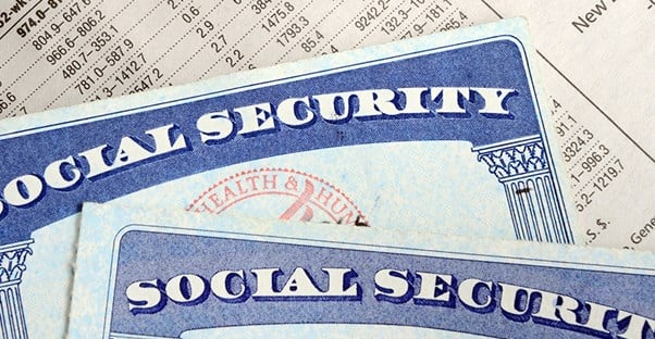 Two social security cards laying on top of a printed chart of numbers showing amount of identity theft around the world