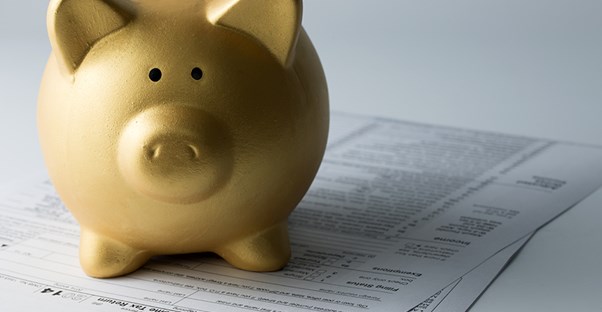 a golden piggy bank sitting on top of tax filing documents on a tax preparer's desk