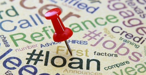 various financial terms printed on a piece of paper with a push pin selecting the word loan