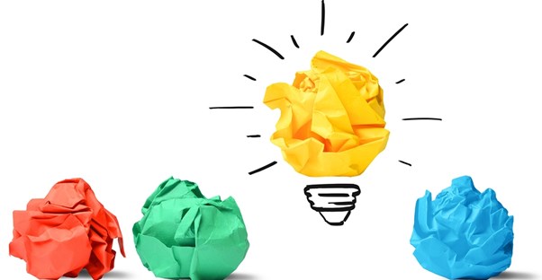 Wads of red, green, and blue paper lying next to a yellow wad of paper turned into a light bulb representing a brilliant business idea