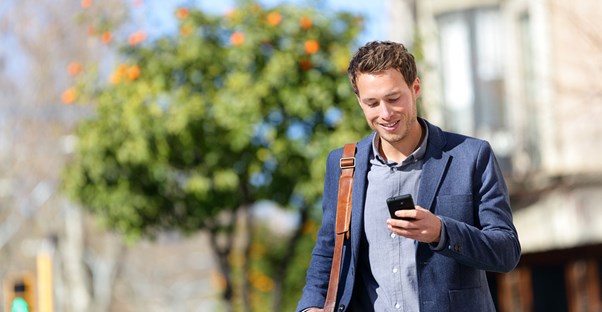 Man smiling as he checks his bank balance from a smartphone budgeting app