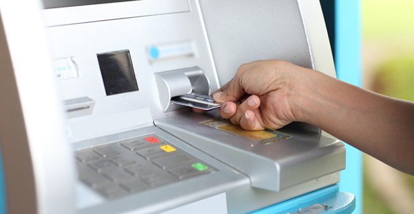 Close up of someone inserting a credit card into an ATM to represent the fees associated with credit card processing.