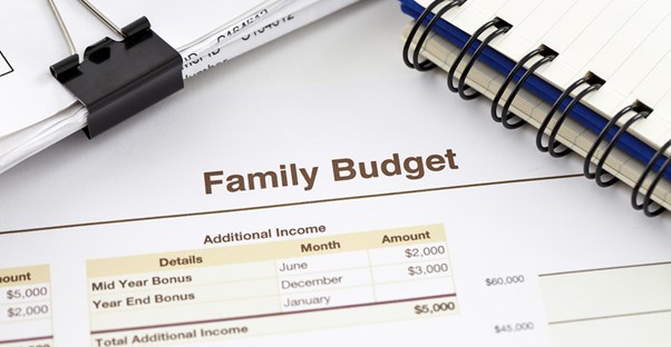 A family budget, notebook, and paperclipped receipts piled on a table after someone worked out their family budget.