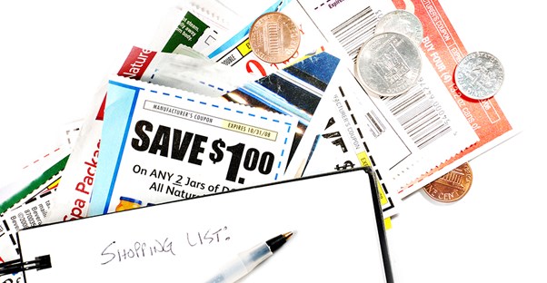 A pile of coupons and coins and a pen laying on table after a woman started couponing.