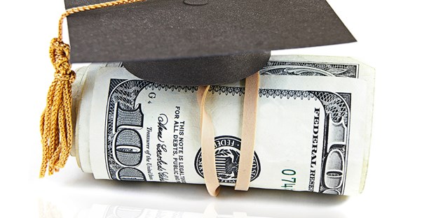 A miniature graduation cap sitting on top of a roll of money received from college scholarships.