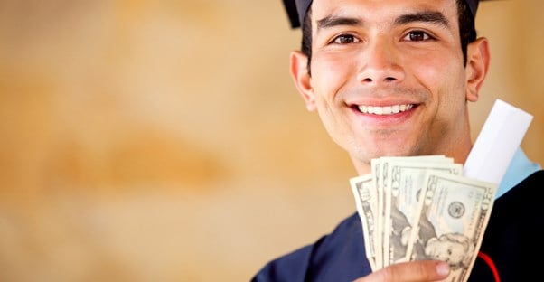 A college grad smiles while holding the money he got through a college loan because of the advantages it offered to him.