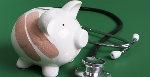 Piggy bank with band-aids sitting by a stethoscope