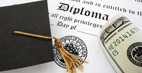 Graduation cap and hundred dollar bill sitting on a diploma