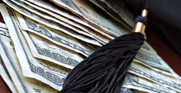 Graduation tassel framing hundred dollar bills used to pay student loans