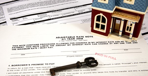 Miniature home and key on top of home equity loan paperwork