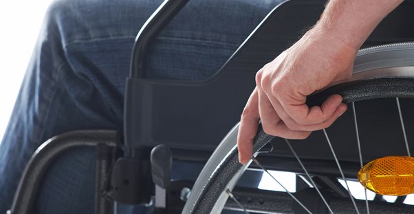A hand rests on the wheel of a wheelchair