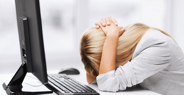 Blonde girl violently bangs her head against her desk in frustration