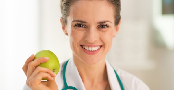 A dietitian holds an apple and smiles
