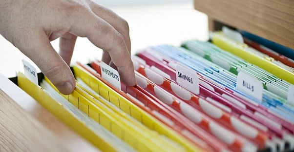 A hand sorts through color coded files