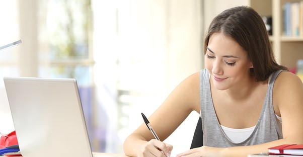 a young woman takes notes from an online lsat prep course on her laptop