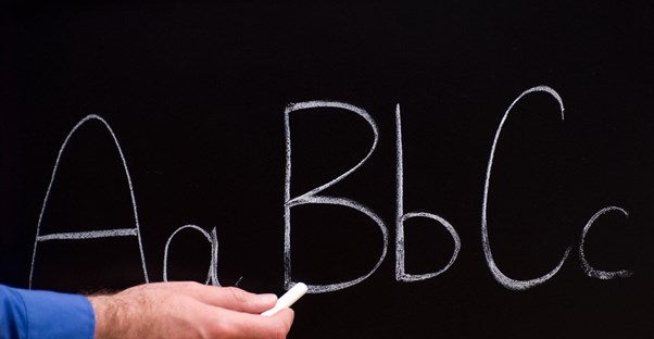 Teacher write ABCs on a chalkboard