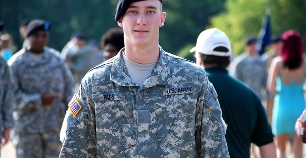 A soldier stops and smiles at the camera