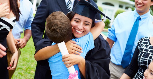 A happy graduate hugs a young boy