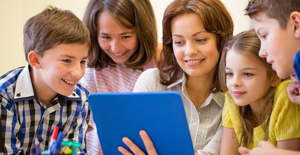 A teacher shows her students how to use a tablet