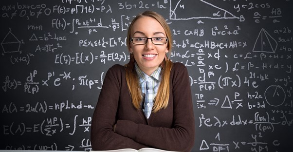 A young college student studies for the GRE in a classroom in front of a chalk board