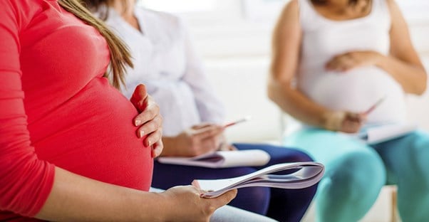 Pregnant women wait in a waiting room for their appointments.