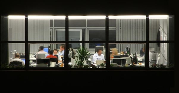 a busy office seen through a window at night