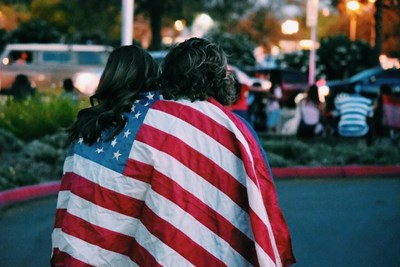 two young women drape and american flag over their shoulders
